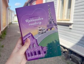 Rakkauden roadtrip -kirjan kansi pirteän violetti ja siinä on matkailuauto Eiffel-tornin ja Colosseumin välissä